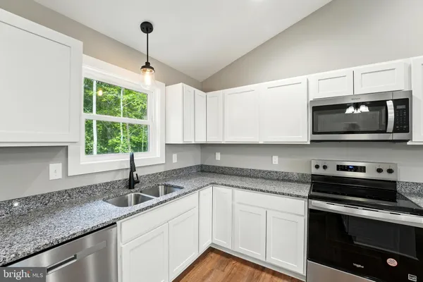 a kitchen with stainless steel appliances granite countertop a sink a stove and microwave