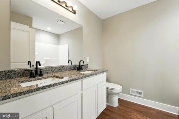 a bathroom with a granite countertop sink a toilet and a mirror