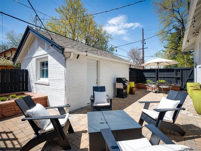 a view of a patio with a dining table and chairs under an umbrella with a barbeque