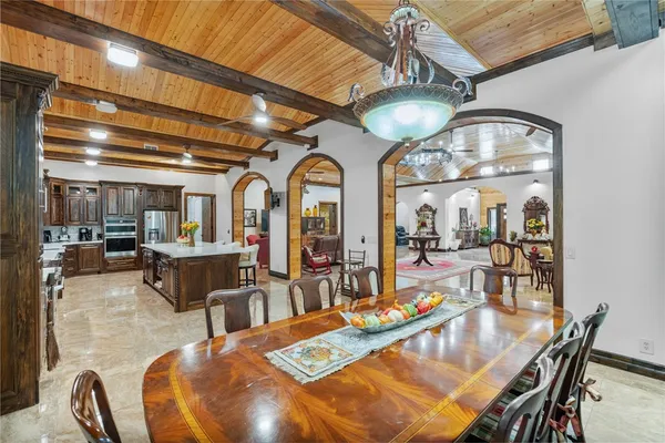 a living room with furniture a chandelier and a dining table with wooden floor