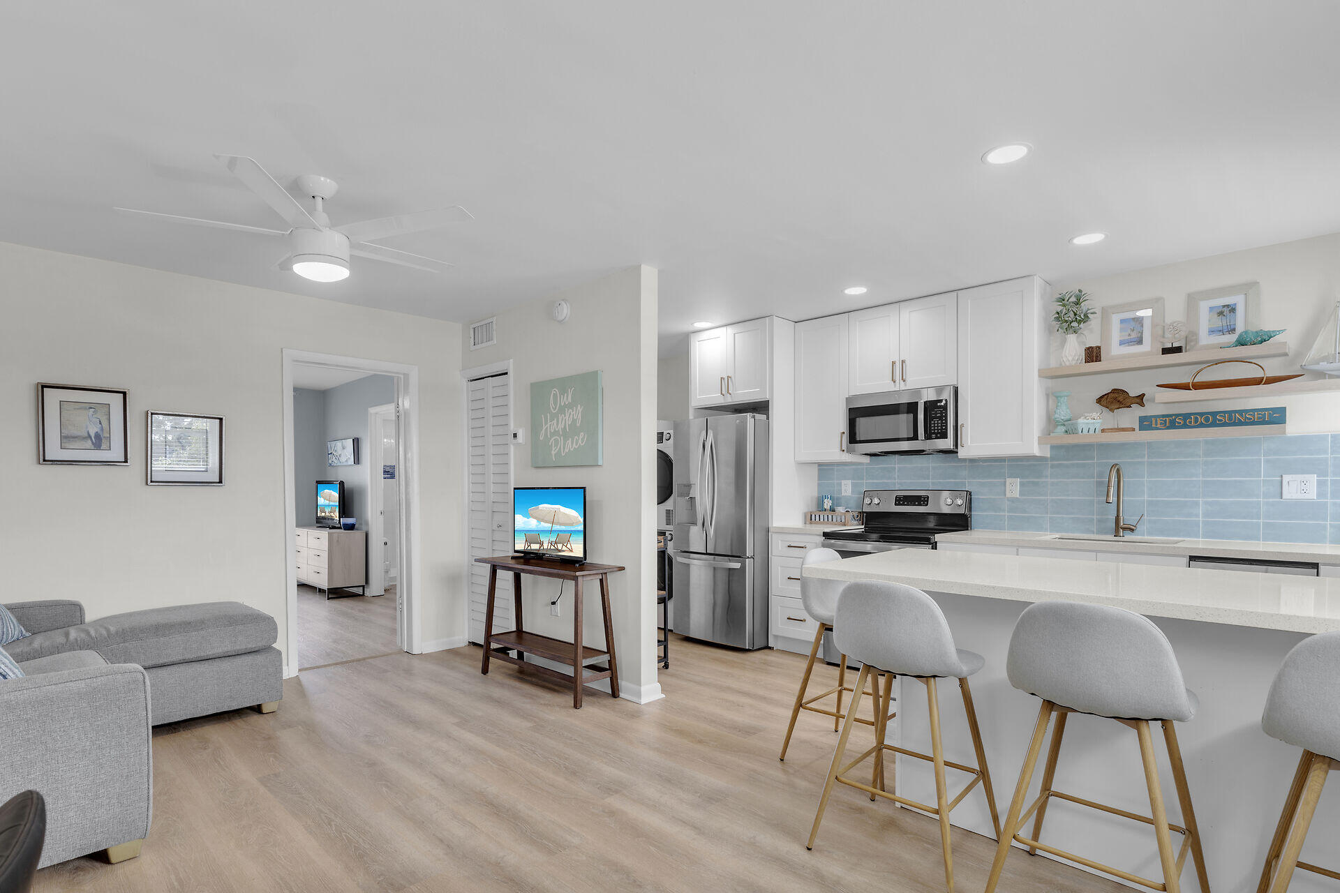 201 Coppitt Road, Unit 203B Key West, FL 33040 - Photo 16 of 44 a kitchen with stainless steel appliances a stove a refrigerator a kitchen island a dining table and chairs with wooden floor