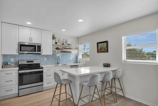 a kitchen with stainless steel appliances kitchen island granite countertop a stove top oven a sink a counter space and cabinets