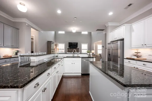 a large kitchen with stainless steel appliances granite countertop a lot of counter space and wooden floor