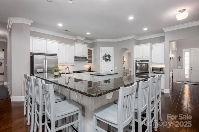 a kitchen with stainless steel appliances granite countertop a kitchen island a stove a refrigerator a stove a sink a table and chairs