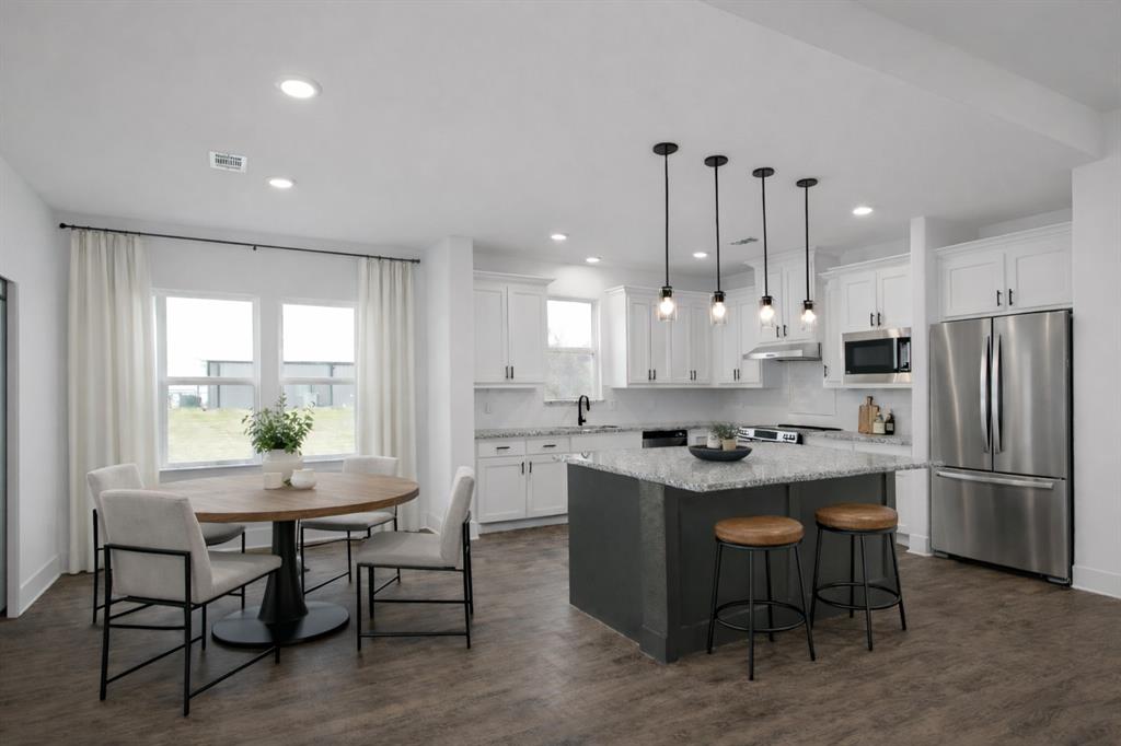 71 Arkansas Road Sadler, TX 76264 - Photo 13 of 35 a kitchen with kitchen island a dining table chairs stainless steel appliances and windows
