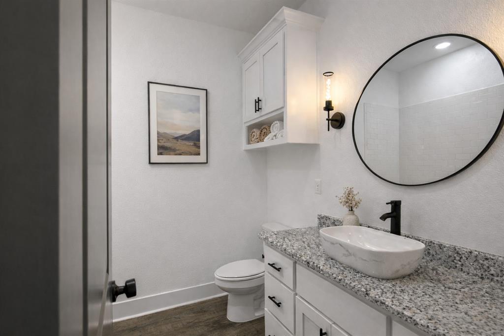 71 Arkansas Road Sadler, TX 76264 - Photo 23 of 35 a bathroom with a granite countertop toilet a sink and a mirror