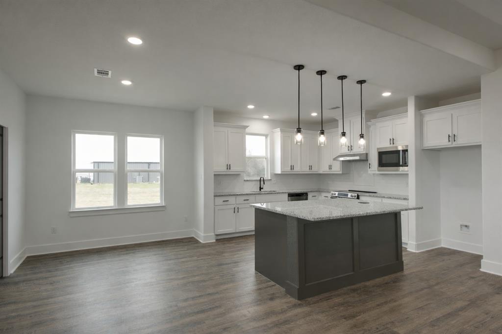 71 Arkansas Road Sadler, TX 76264 - Photo 10 of 35 a kitchen with a stove a sink a refrigerator and white cabinets with wooden floor