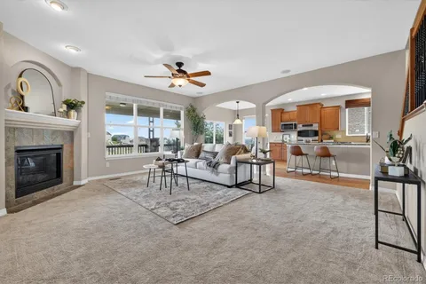 a living room with furniture a rug kitchen view and a large window