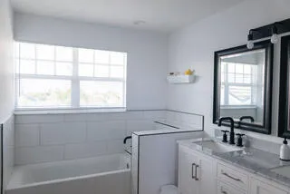 a bathroom with a granite countertop sink mirror vanity and a bathtub