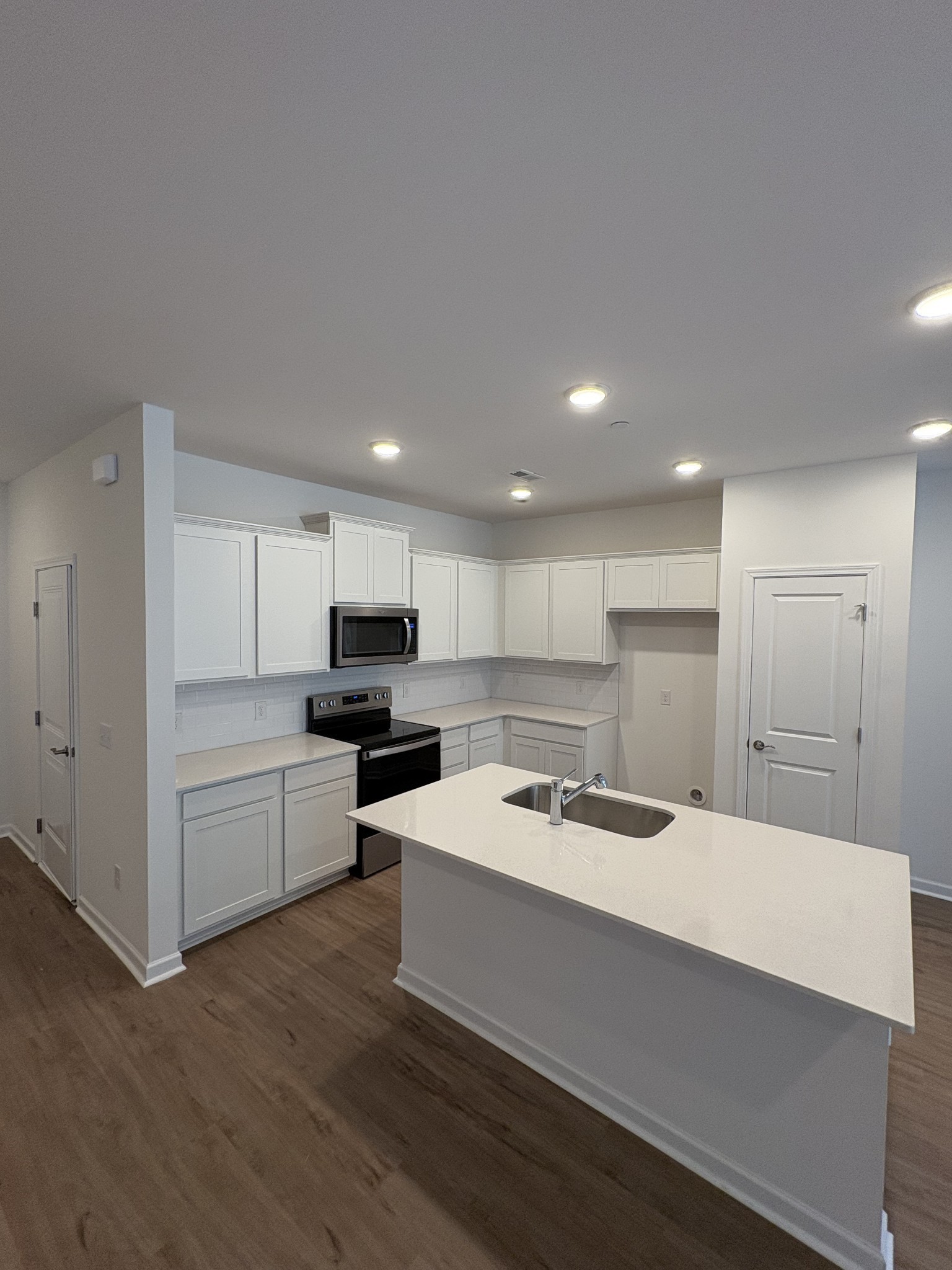 7144 Mapleside Lane, Unit 19 Fairview, TN 37062 - Photo 2 of 26 a kitchen with a sink a stove a refrigerator and white cabinets with wooden floor