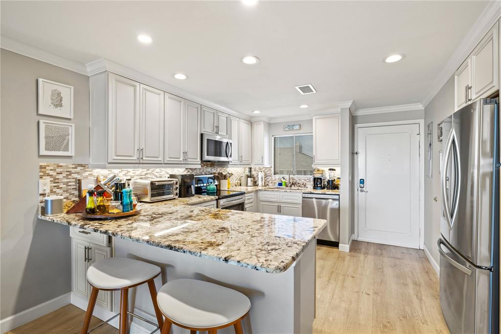 1602 Stickney Point Road, Unit 307 Sarasota, FL 34231 - Photo 4 of 56 a kitchen with stainless steel appliances granite countertop a refrigerator and a stove top oven