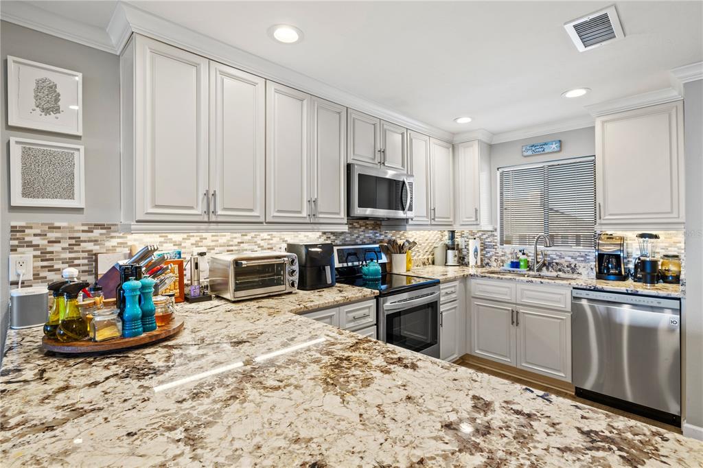 1602 Stickney Point Road, Unit 307 Sarasota, FL 34231 - Photo 5 of 56 a kitchen with stainless steel appliances granite countertop a stove top oven a sink dishwasher and cabinets