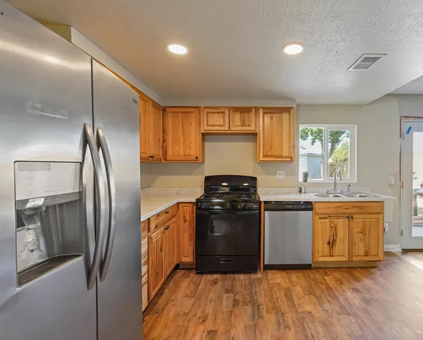 a kitchen with granite countertop a refrigerator stove top oven and sink