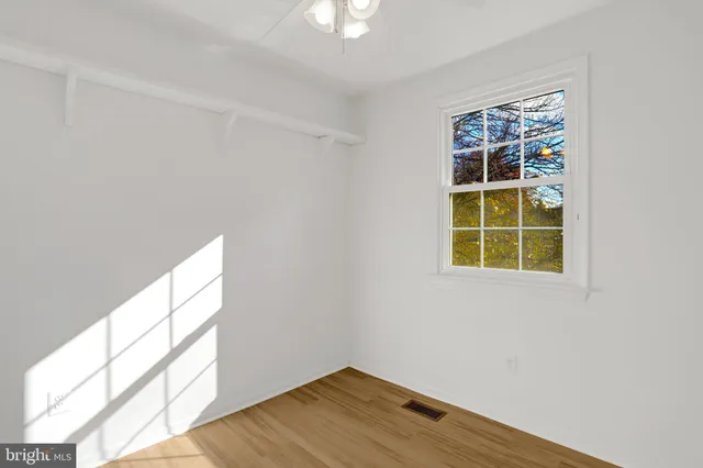 a view of an empty room with wooden floor and a hallway