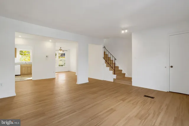a view of an empty room with wooden floor and stairs