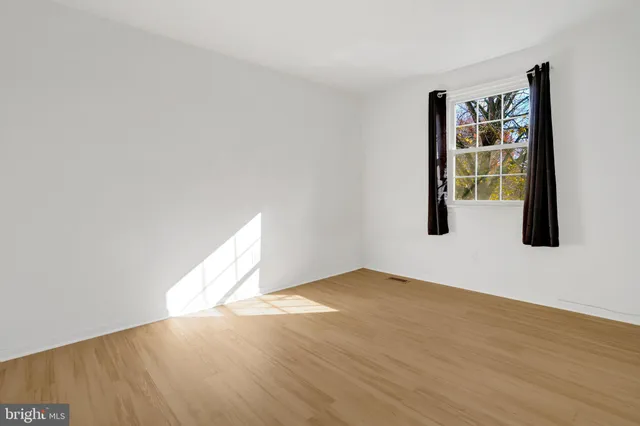 a view of an empty room with window and wooden floor