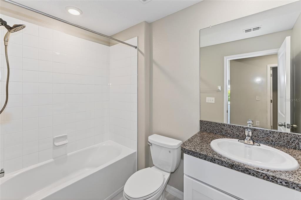 16751 Delia Street Wimauma, FL 33598 - Photo 16 of 36 a bathroom with a granite countertop sink toilet and shower