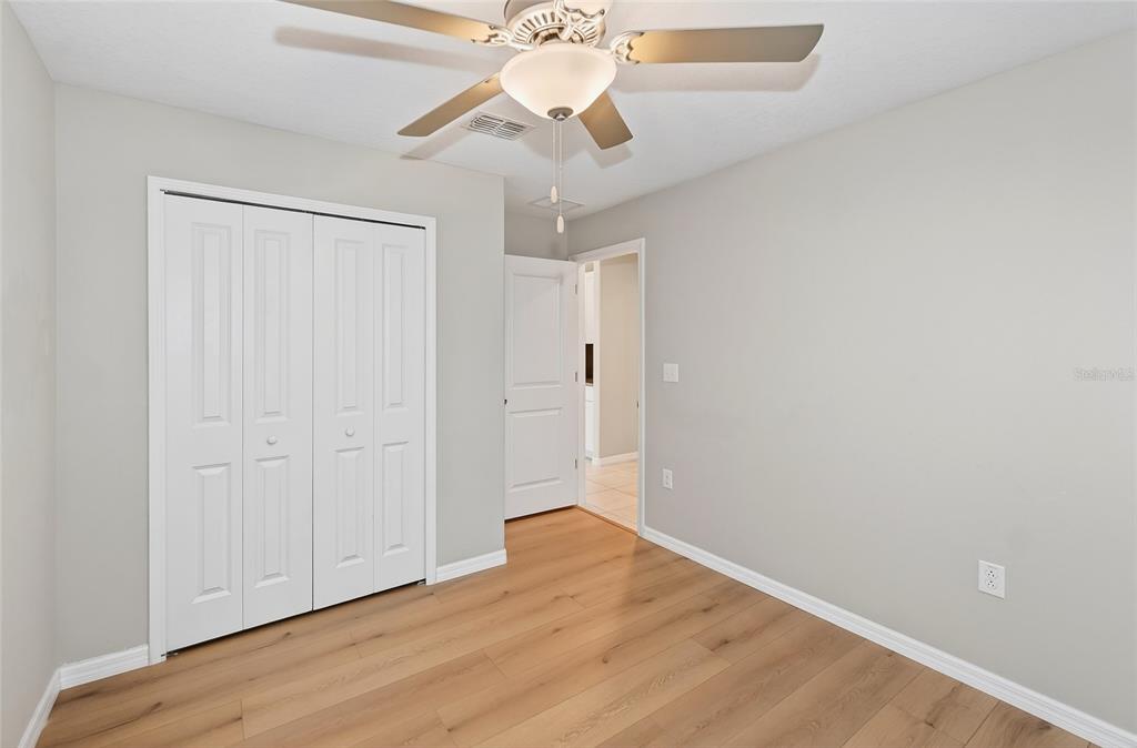 16751 Delia Street Wimauma, FL 33598 - Photo 18 of 36 an empty room with wooden floor chandelier fan and closet area