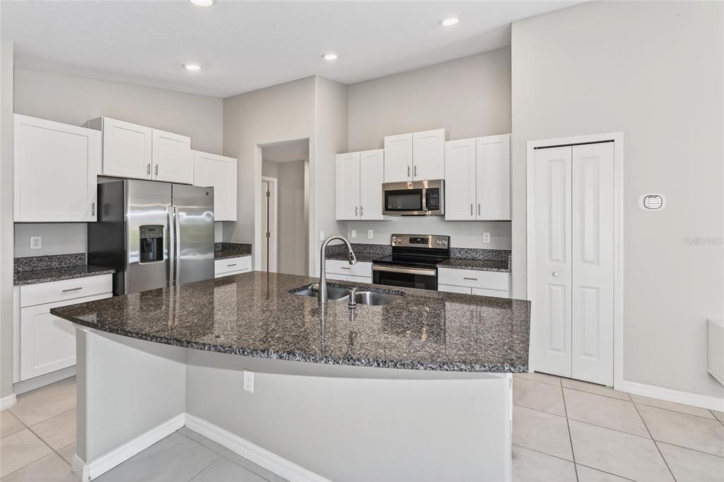 16751 Delia Street Wimauma, FL 33598 - Photo 4 of 36 a kitchen with kitchen island granite countertop a stove a sink and a refrigerator
