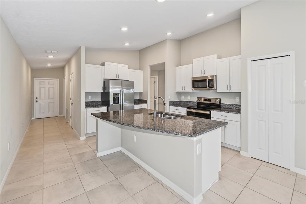 16751 Delia Street Wimauma, FL 33598 - Photo 5 of 36 a view of a kitchen with kitchen island granite countertop a stove top oven a sink a counter top space and cabinets