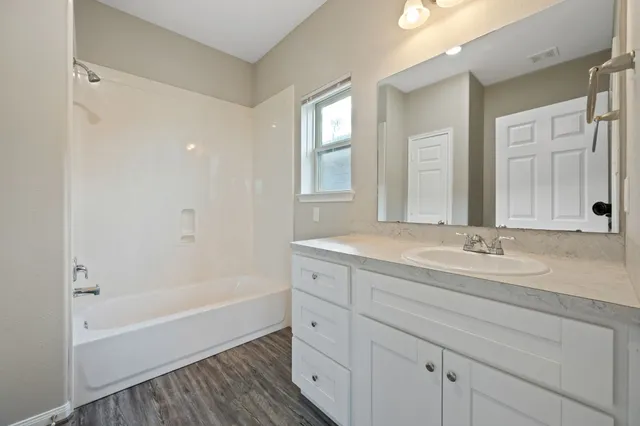 a bathroom with a tub sink and mirror