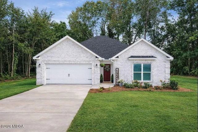 a view of a house with a yard potted plants and a large tree