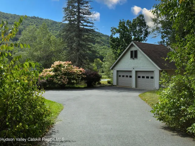 a view of a house with a small yard and large trees