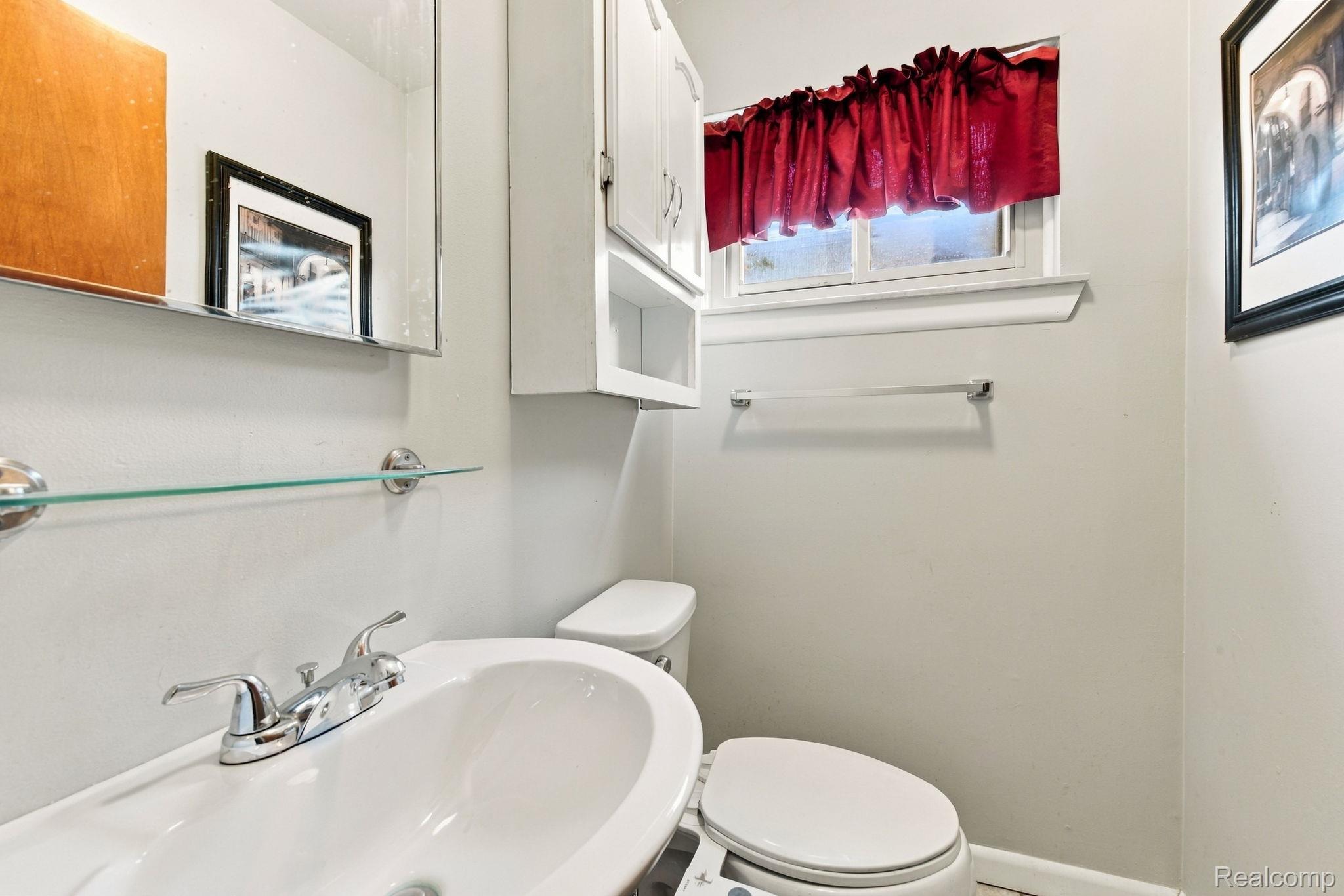 13265 12 Mile Road Warren, MI 48088 - Photo 24 of 33 White ceramic sink with chrome faucet, wall-mounted mirror, glass shelf, and white cabinetry