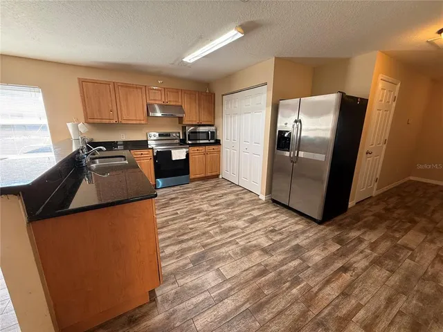 a kitchen with granite countertop a refrigerator and a stove top oven