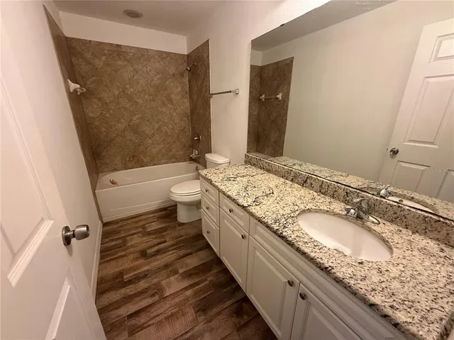 a bathroom with a granite countertop double vanity sink a mirror and a toilet