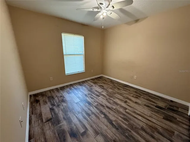 an empty room with wooden floor closet and fan
