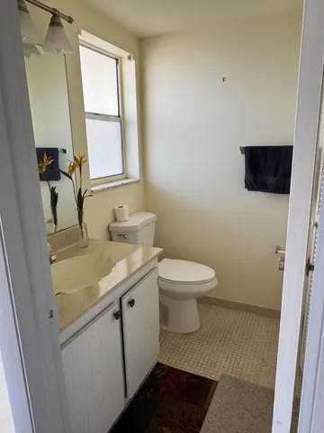 a bathroom with a granite countertop toilet sink and mirror
