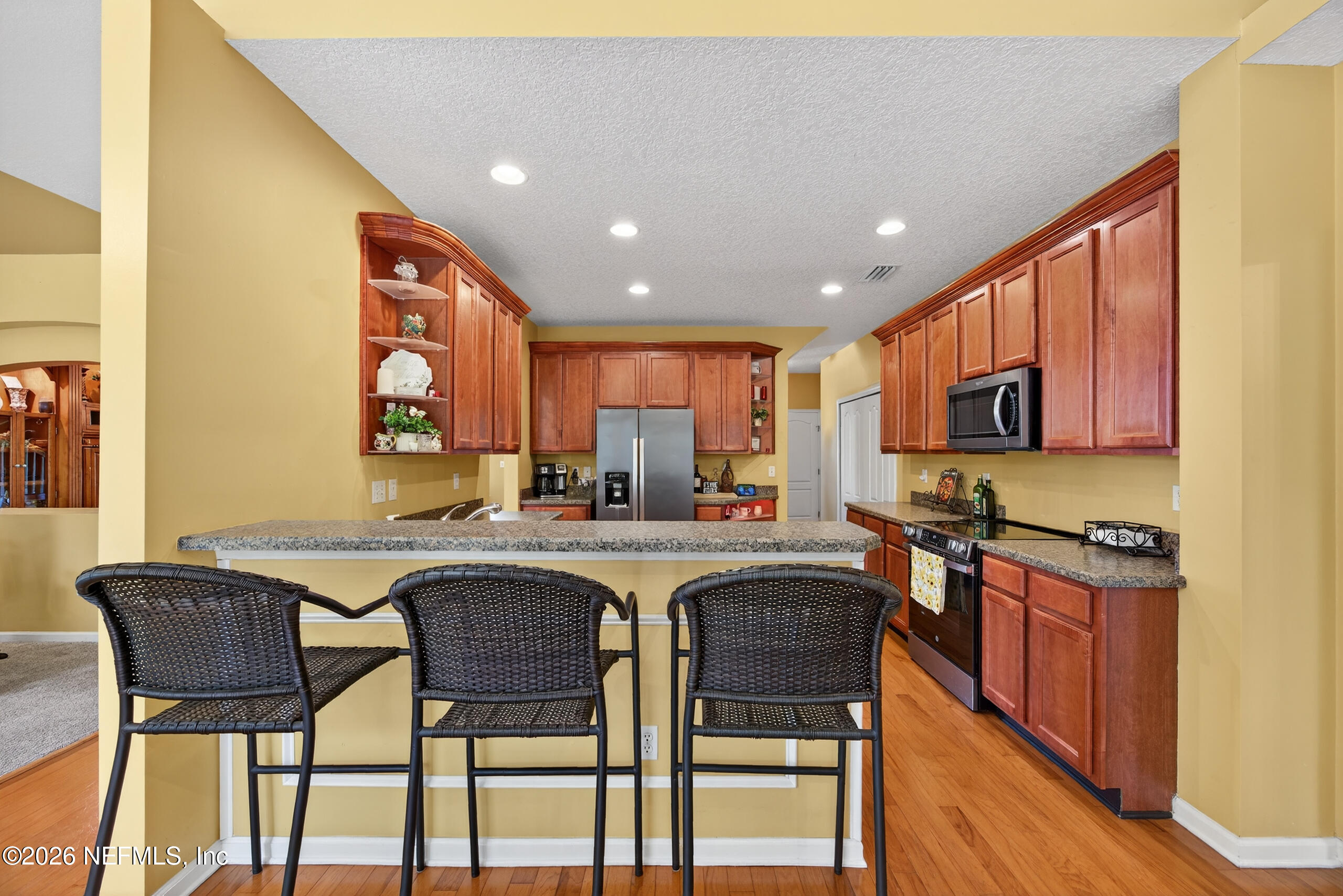 588 Reflection Cove Road Jacksonville, FL 32218 - Photo 14 of 53 a open kitchen with stainless steel appliances granite countertop a stove top oven a sink a dining table and chairs with wooden floor