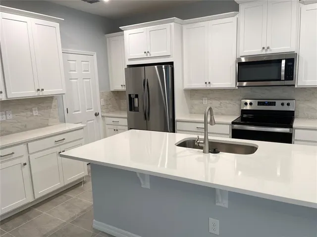 a kitchen with sink a microwave and cabinets