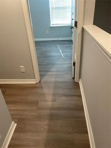 a view of a hallway with wooden floor and staircase