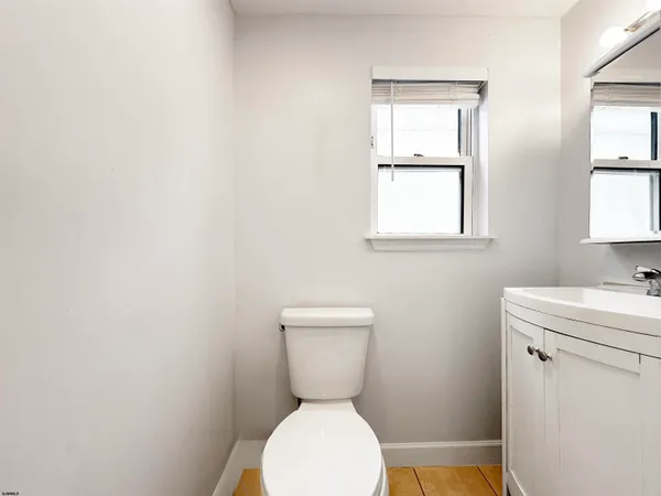 a bathroom with a toilet a sink a window and mirror