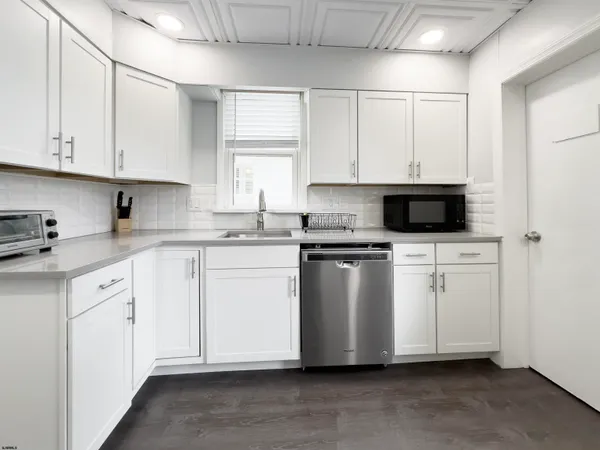 a kitchen with white cabinets white stainless steel appliances and sink