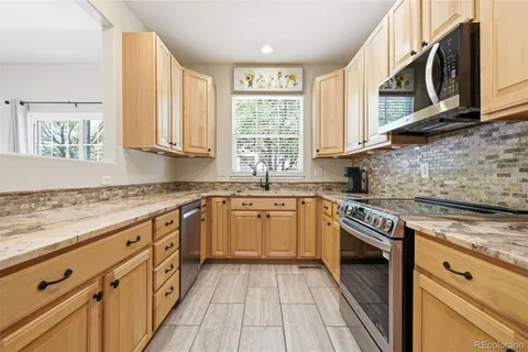 a kitchen with granite countertop a sink cabinets stainless steel appliances and a window