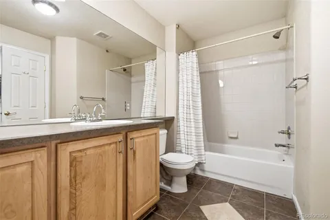 a bathroom with a granite countertop sink a toilet a mirror and a bathtub