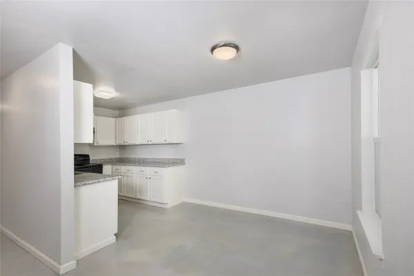 an empty room with chandelier fan and windows
