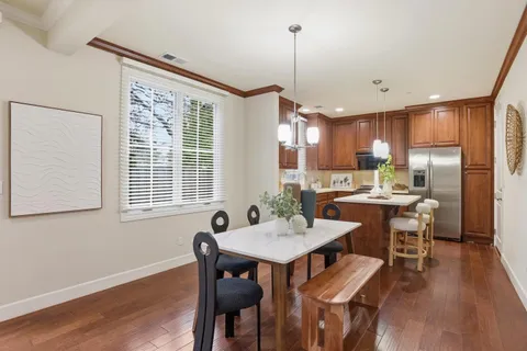 a kitchen with a table chairs refrigerator and wooden floor