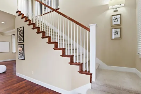 a view of staircase with lots of frames on wall and wooden floor