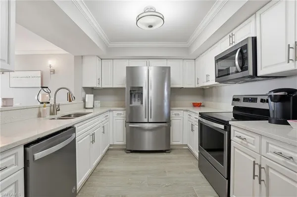 a kitchen with stainless steel appliances granite countertop white cabinets a sink a stove a microwave and refrigerator