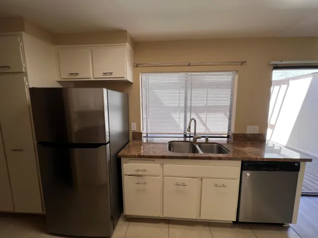 a kitchen with stainless steel appliances granite countertop a refrigerator a sink and white cabinets