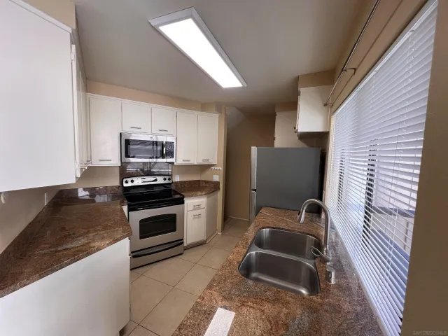 a kitchen with granite countertop a sink and steel appliances