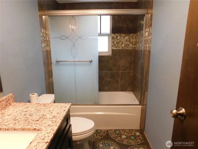 a bathroom with a granite countertop sink toilet and shower