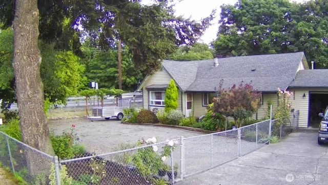 a view of a house with brick walls plants and large tree