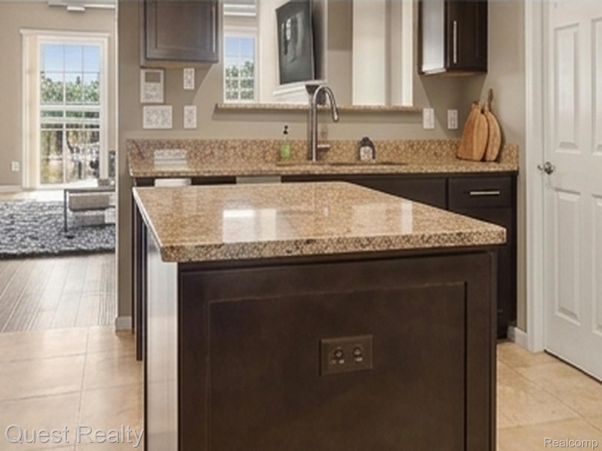218 Mill Street Rochester, MI 48307 - Photo 7 of 28 Kitchen island with a granite countertop, dark wood-finish cabinetry, and a stainless steel sink with a high-arch faucet