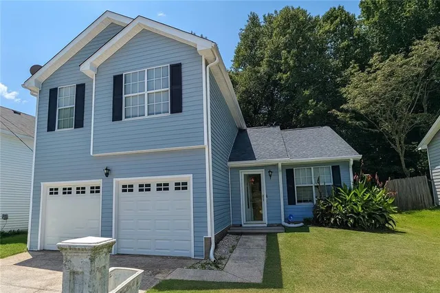 a view of a house with a yard plants and a fountain