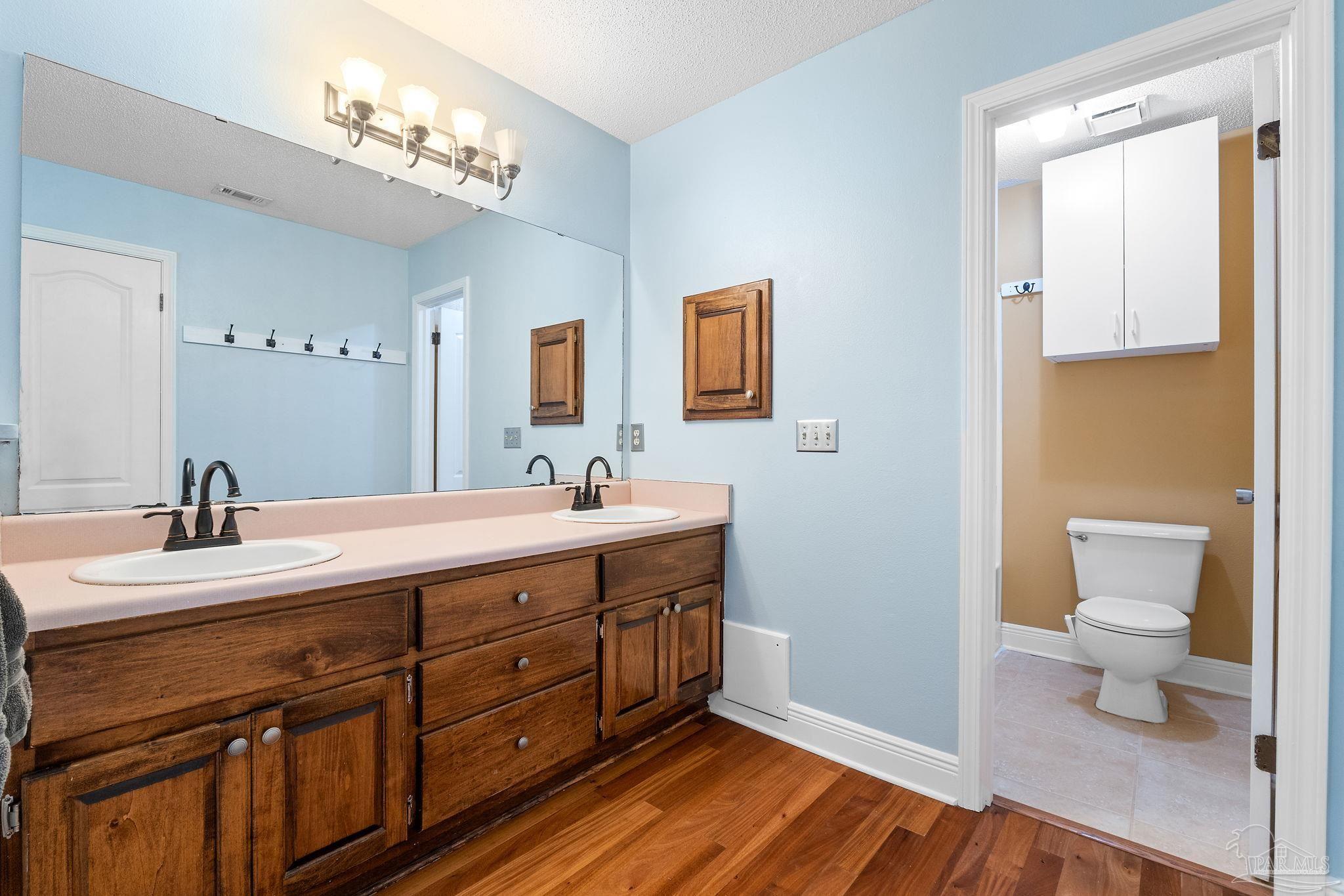 5645 Windham Road Milton, FL 32570 - Photo 20 of 40 a spacious bathroom with a double vanity sink a mirror and a toilet